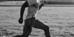 An athlete in full stride running on a track, showcasing determination and speed, with the focus on their form and the track beneath their feet.